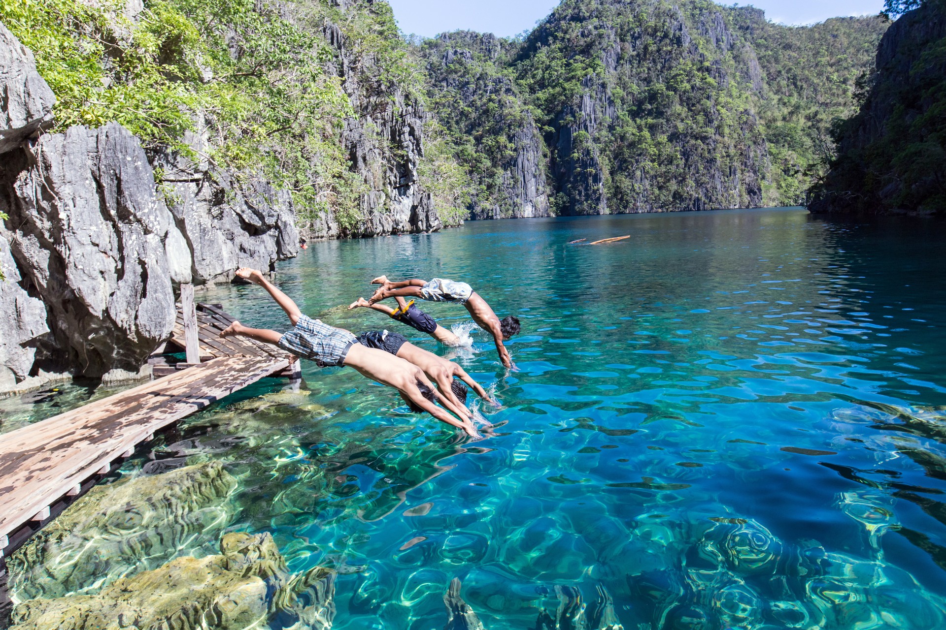 Family with children diving into a lagoon in Palawan