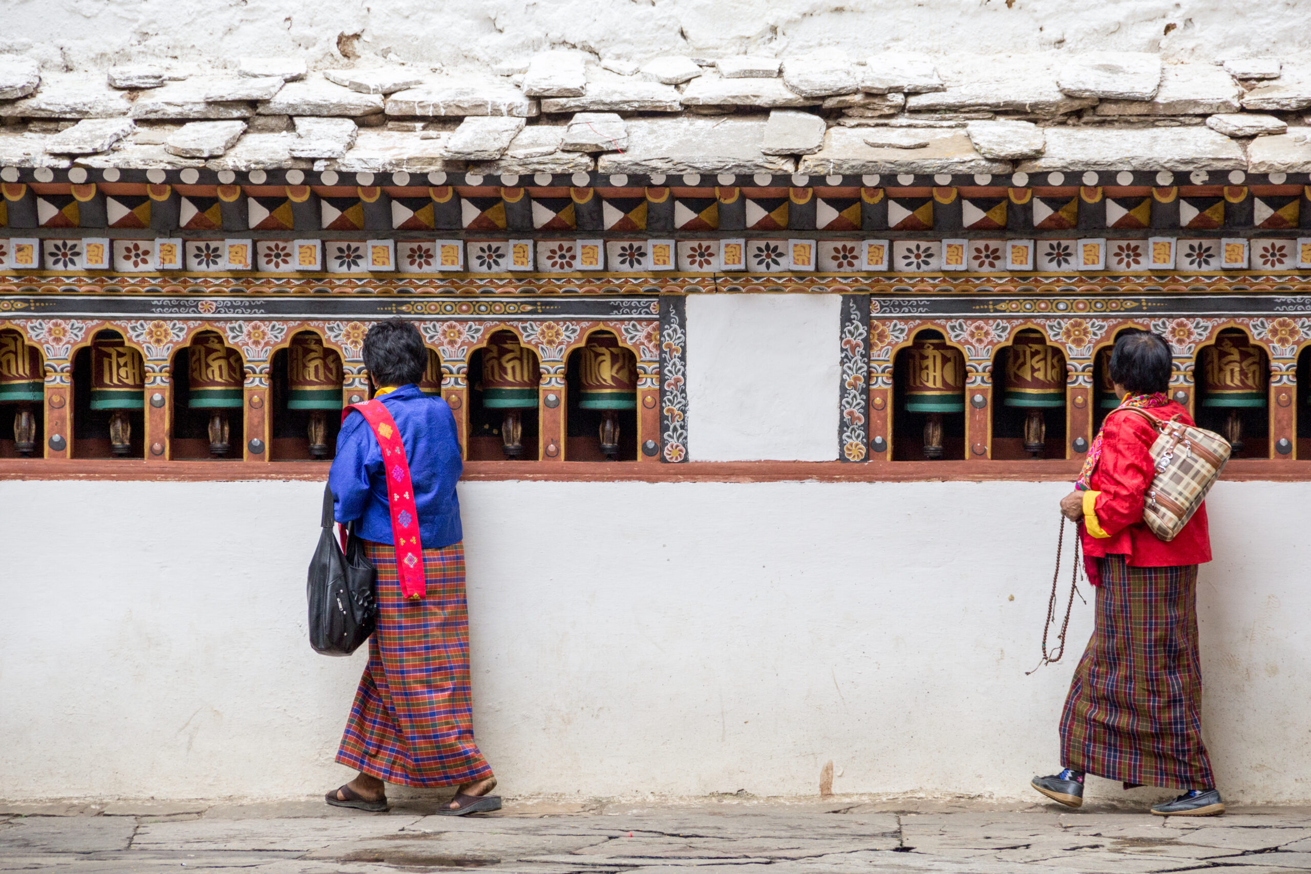 People standing at prayers wheels in Bhutan