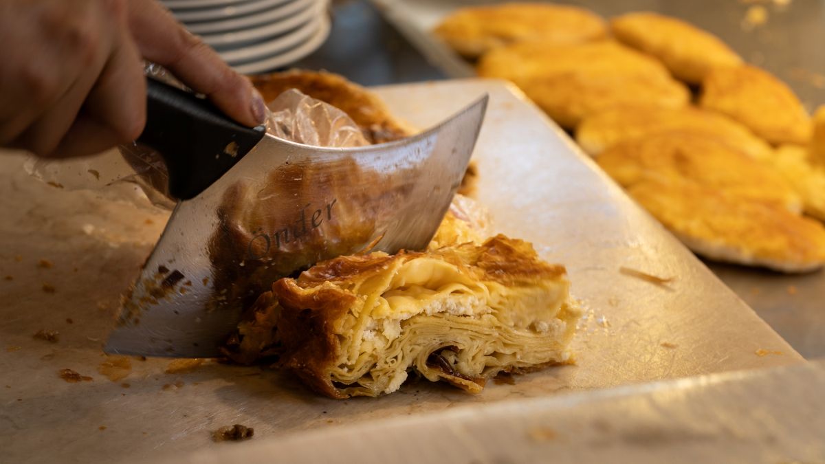 A hand slicing börek pastry