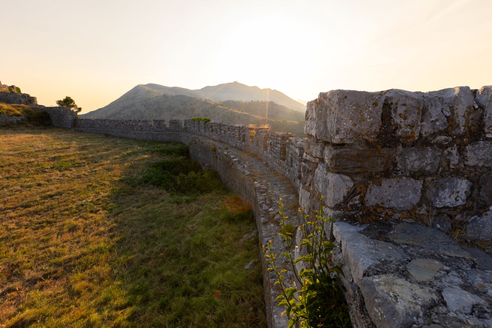 Old stone wall and surrounding landscape bathed in sunlight at Rozafa Castle in Shkodër