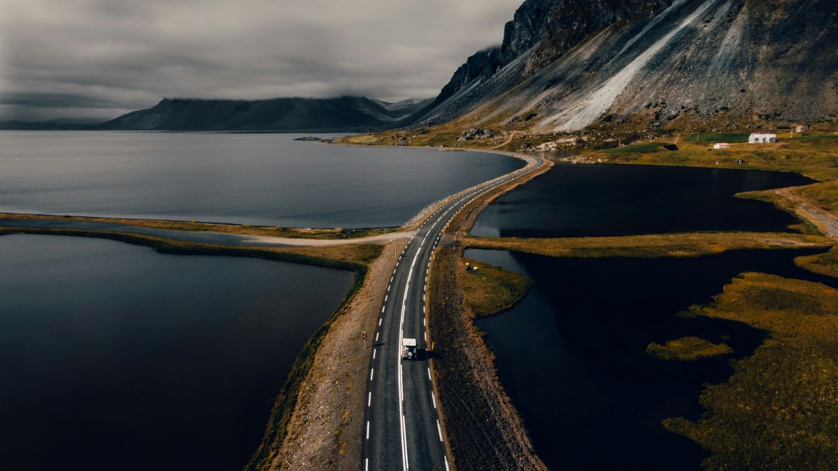 Car driving down an open road surrounded by water in Iceland