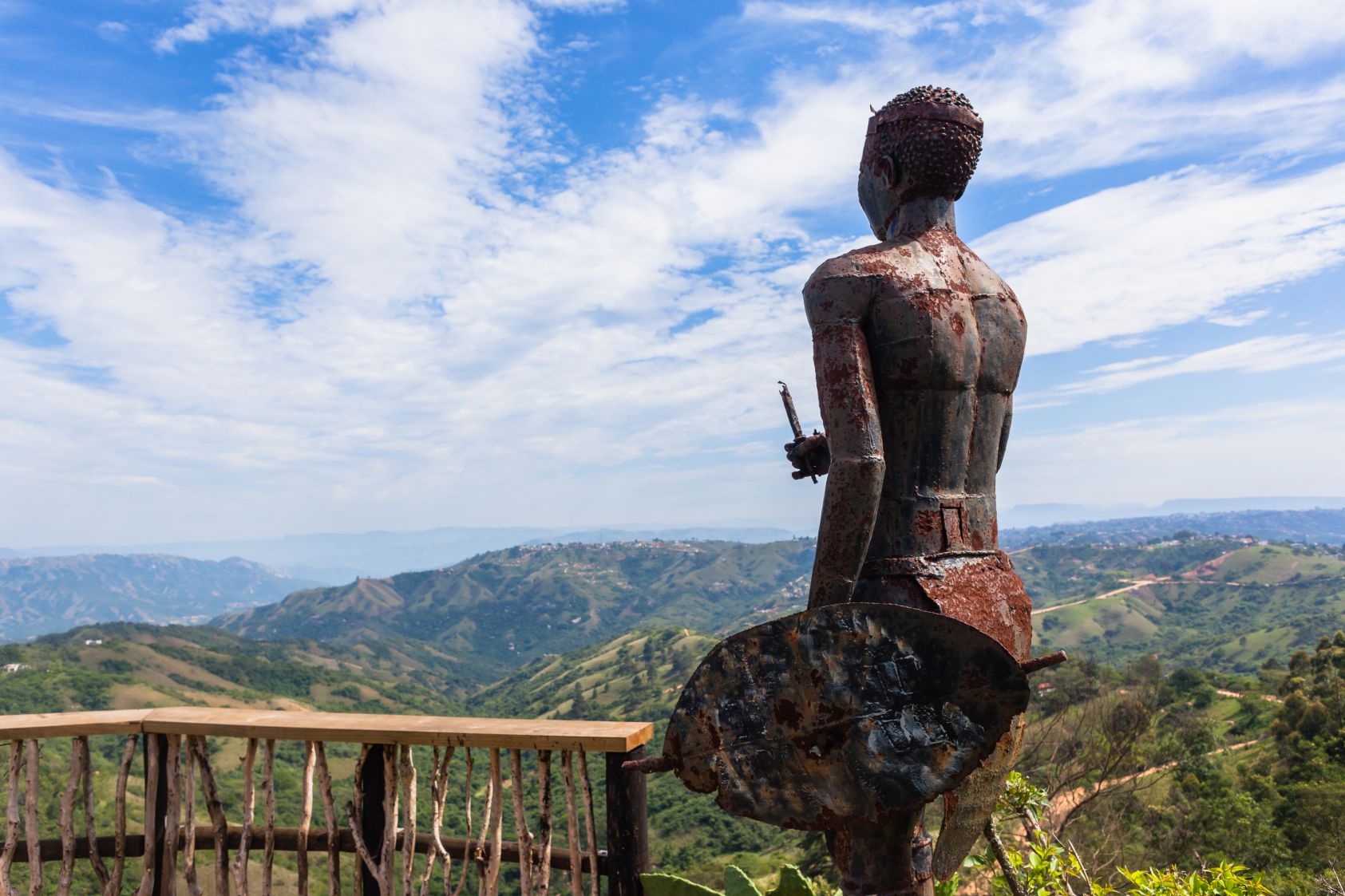 Exploring South African traditions: Zulu metal statue at a viewpoint overlooking vast landscape