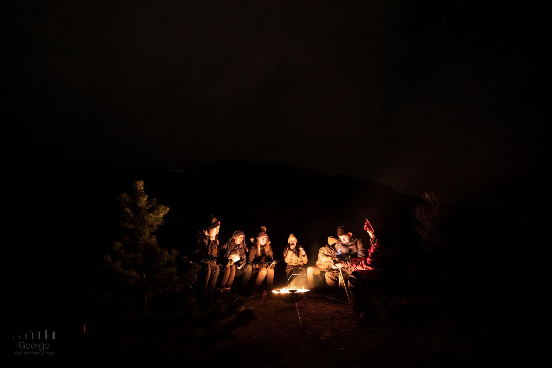 Gathering around a campfire for drinks and reindeer sausage in Scandinavia, one of the most unique foodie travel experiences