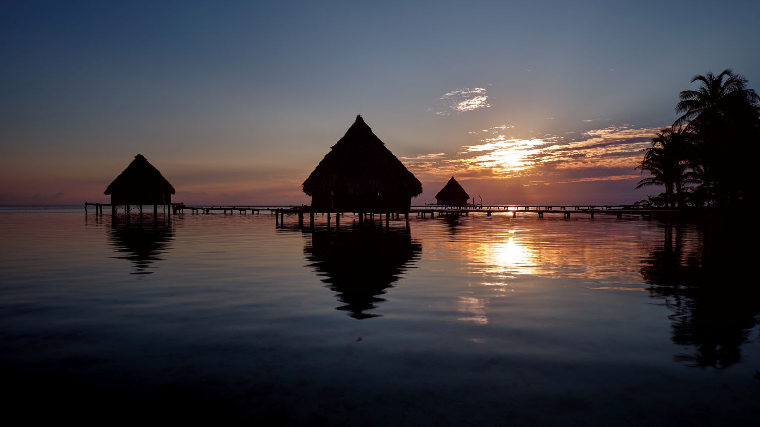 Huts on stilts at sunset in Glover's Reef Atoll